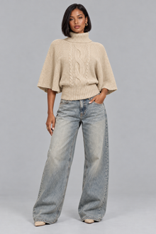 Women's beige cable knit turtleneck jumper, full-length look with wide leg jeans
