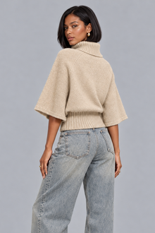 Women's beige cable knit turtleneck jumper with cape sleeves, back view