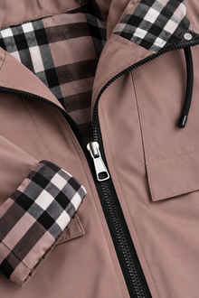 Close-up of brown raincoat zip, hood drawcord and check cuff lining