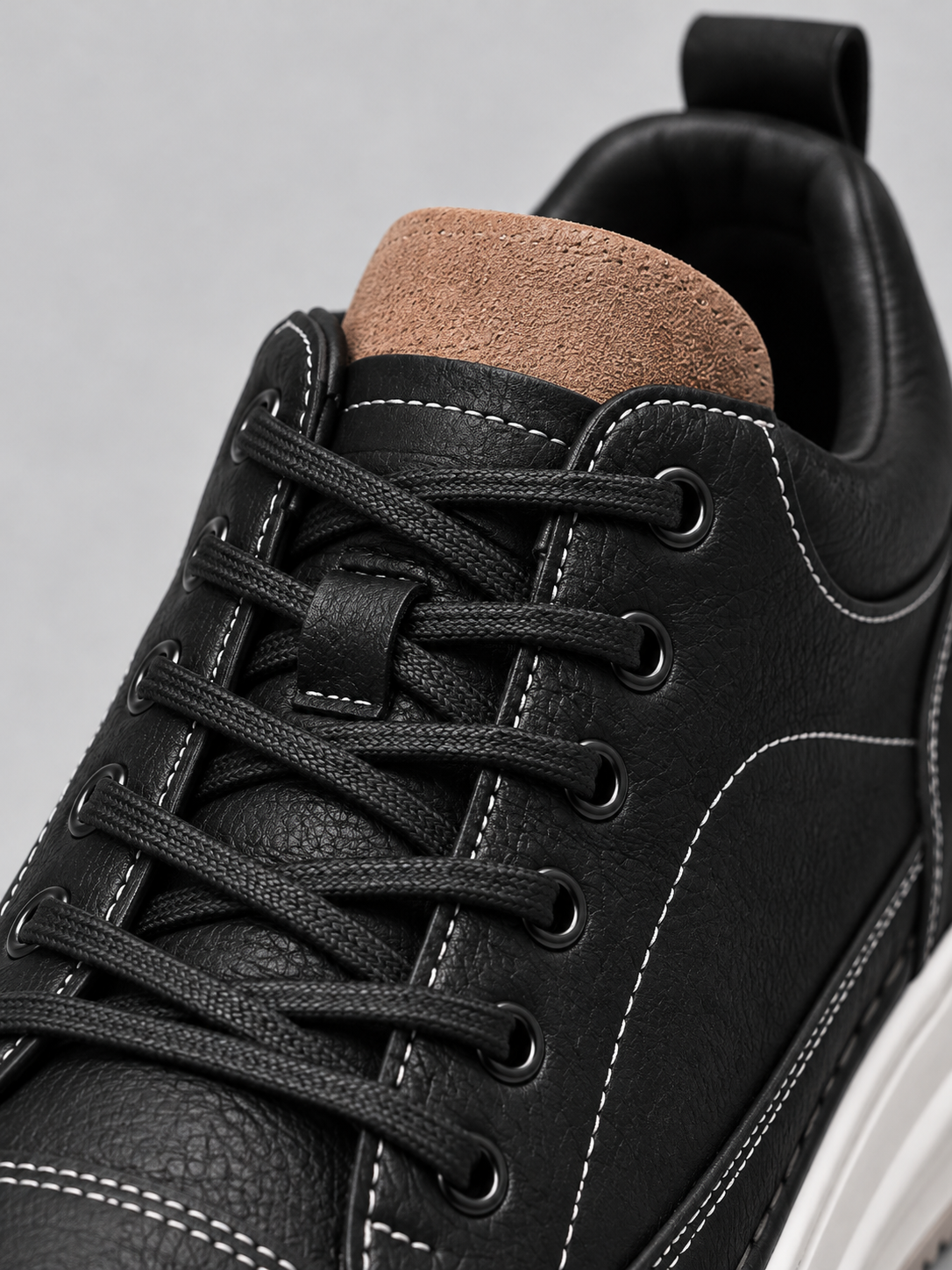 Close-up of black trainer laces, suede tongue and padded collar