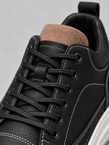 Close-up of black trainer laces, suede tongue and padded collar