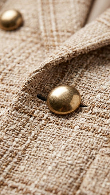 Close-up of tweed blazer fabric and gold button