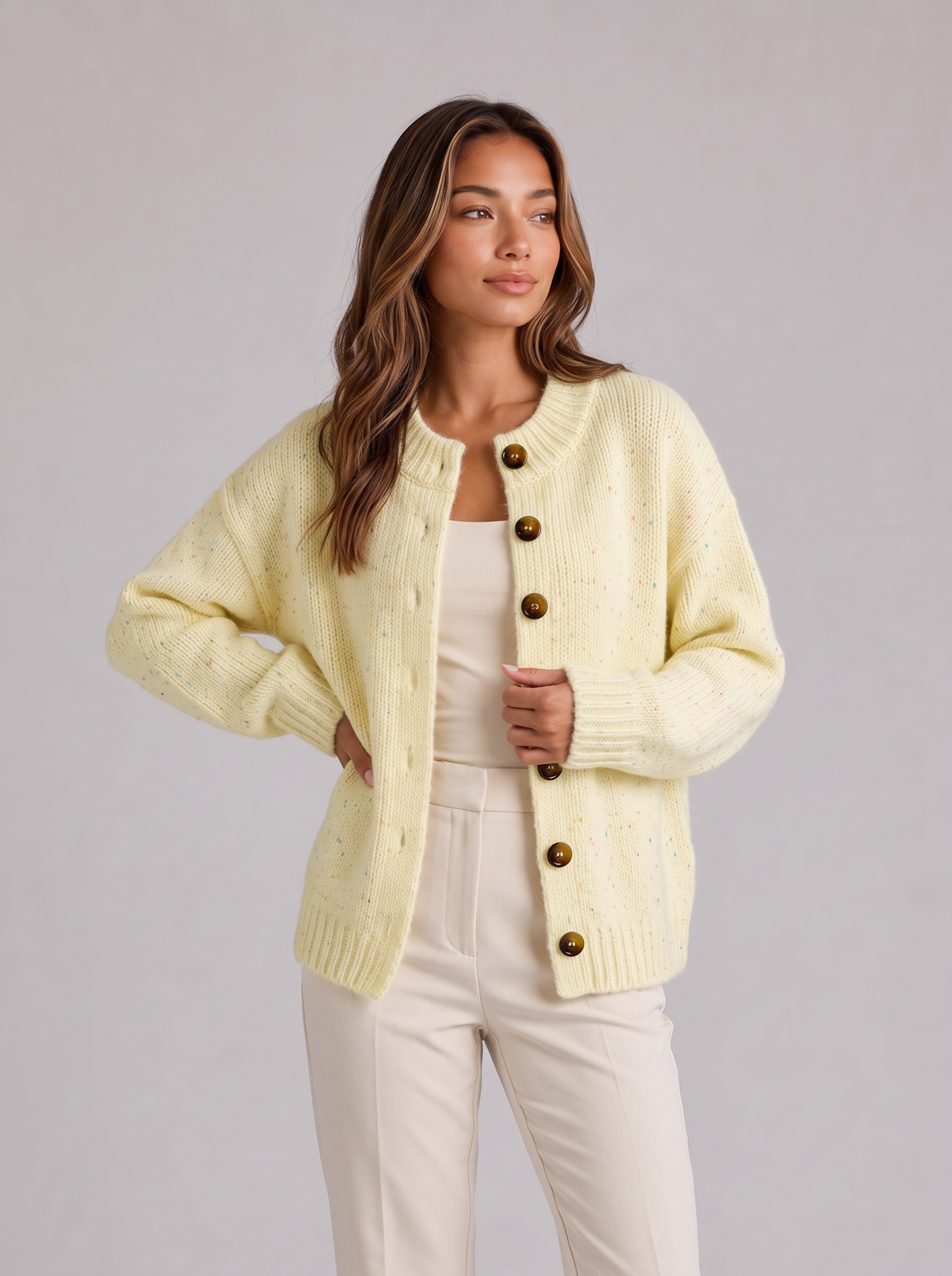 Woman wearing light yellow fluffy knit button-front round neck cardigan with cream trousers