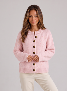 Woman wearing light pink fluffy knit button-front round neck cardigan with cream trousers