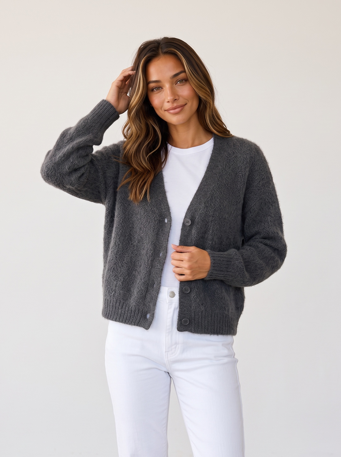 Woman wearing dark grey fluffy knit button-front V-neck cardigan with white jeans