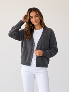 Woman wearing dark grey fluffy knit button-front V-neck cardigan with white jeans