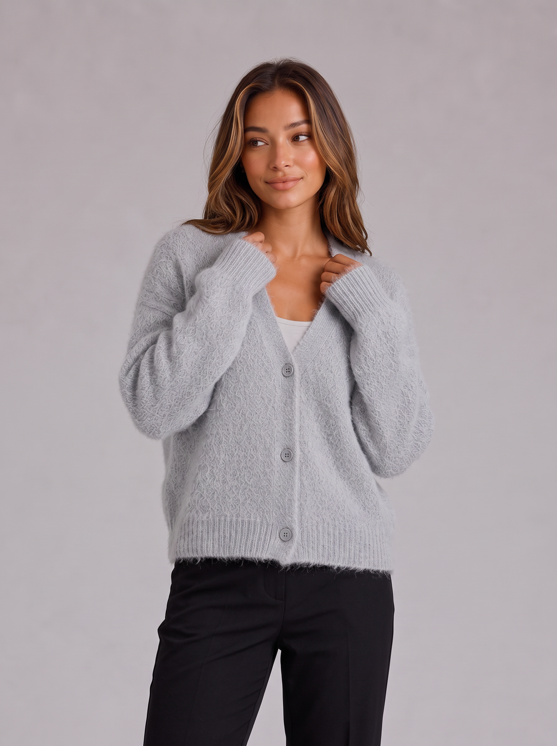 Woman wearing light grey fluffy knit button-front V-neck cardigan with black trousers