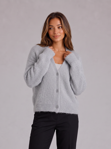 Woman wearing light grey fluffy knit button-front V-neck cardigan with black trousers
