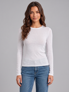 Woman wearing white slim fit round neck long sleeve top with blue jeans, front view