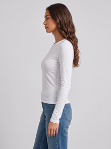 Woman wearing white slim fit round neck long sleeve top, side view