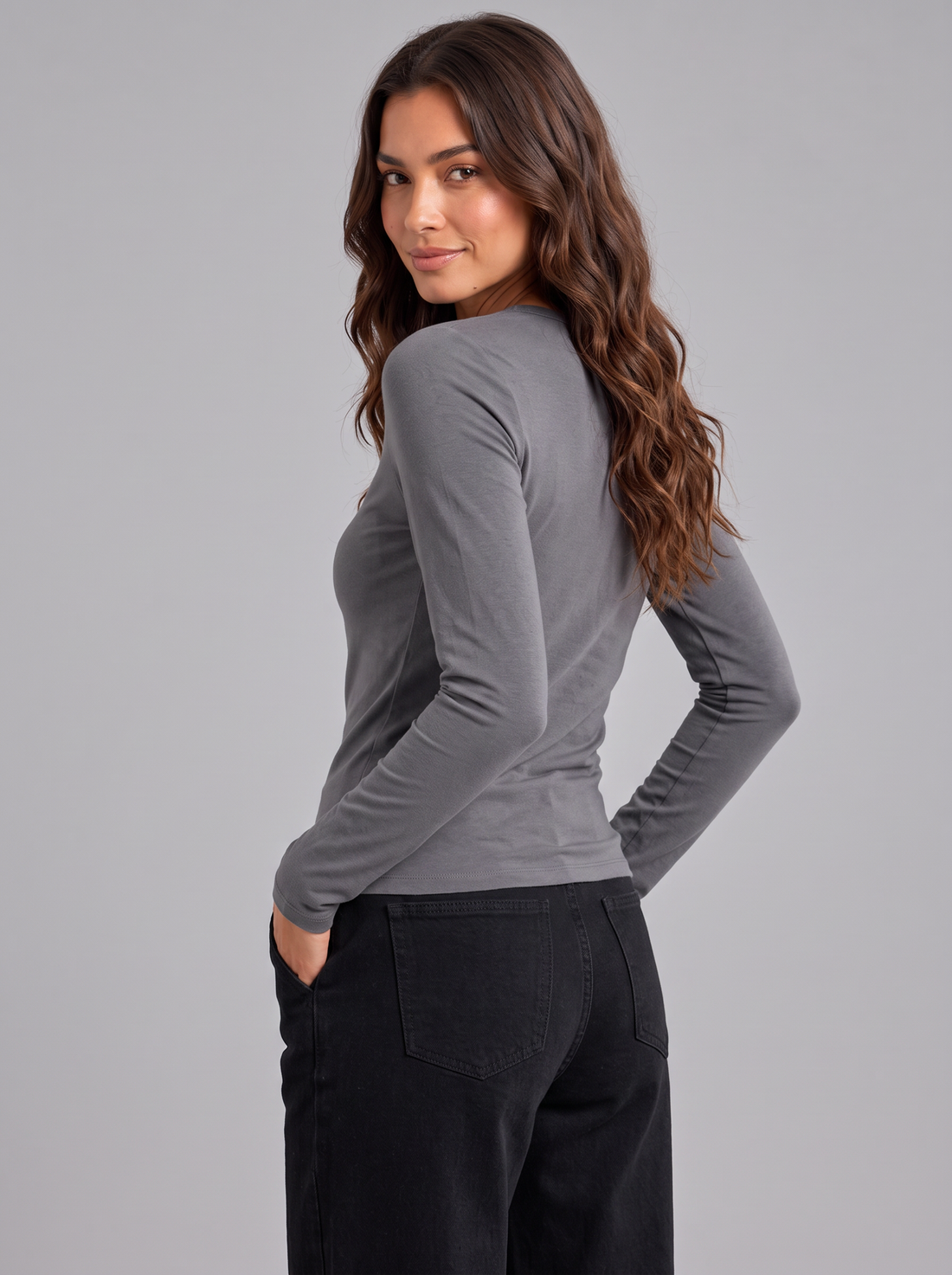 Woman wearing grey slim fit round neck long sleeve top with black trousers