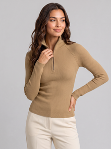 Woman wearing khaki ribbed roll neck long sleeve top with collar zip and cream trousers