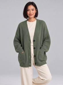 Woman wearing oversized chunky knit button cardigan in green