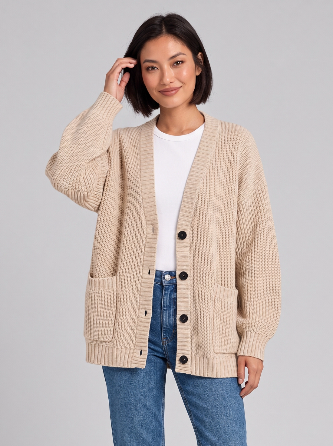 Woman wearing oversized chunky knit button cardigan in beige