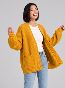 Woman wearing oversized chunky knit button cardigan in turmeric yellow