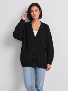 Woman wearing oversized chunky knit button cardigan in black