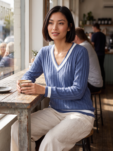 Woman in a cafe wearing violet blue ribbed V-neck contrast trim jumper