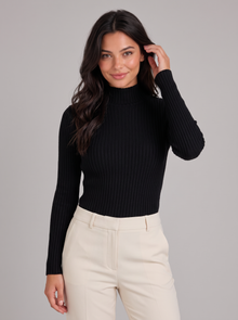 Woman wearing black slim fit ribbed mock neck jumper