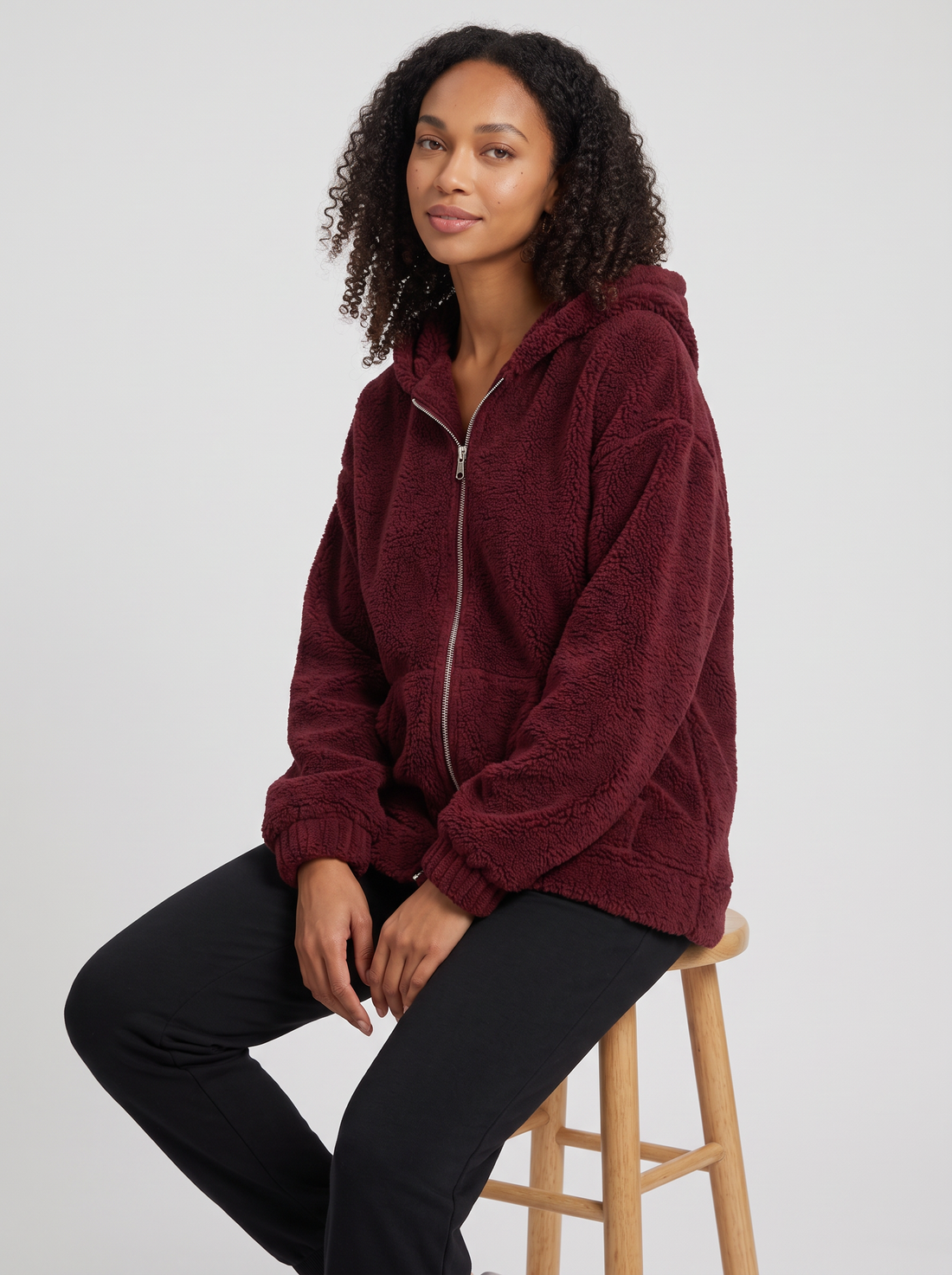 Woman wearing burgundy hooded teddy fleece cardigan with pockets