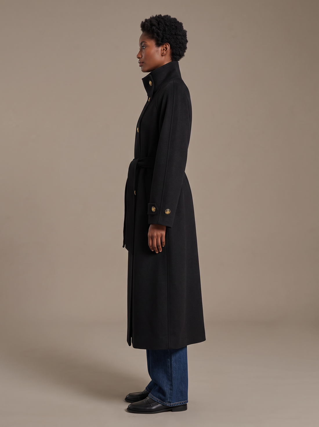 Side view of black longline belted wool coat with button cuffs