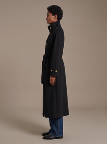 Side view of black longline belted wool coat with button cuffs