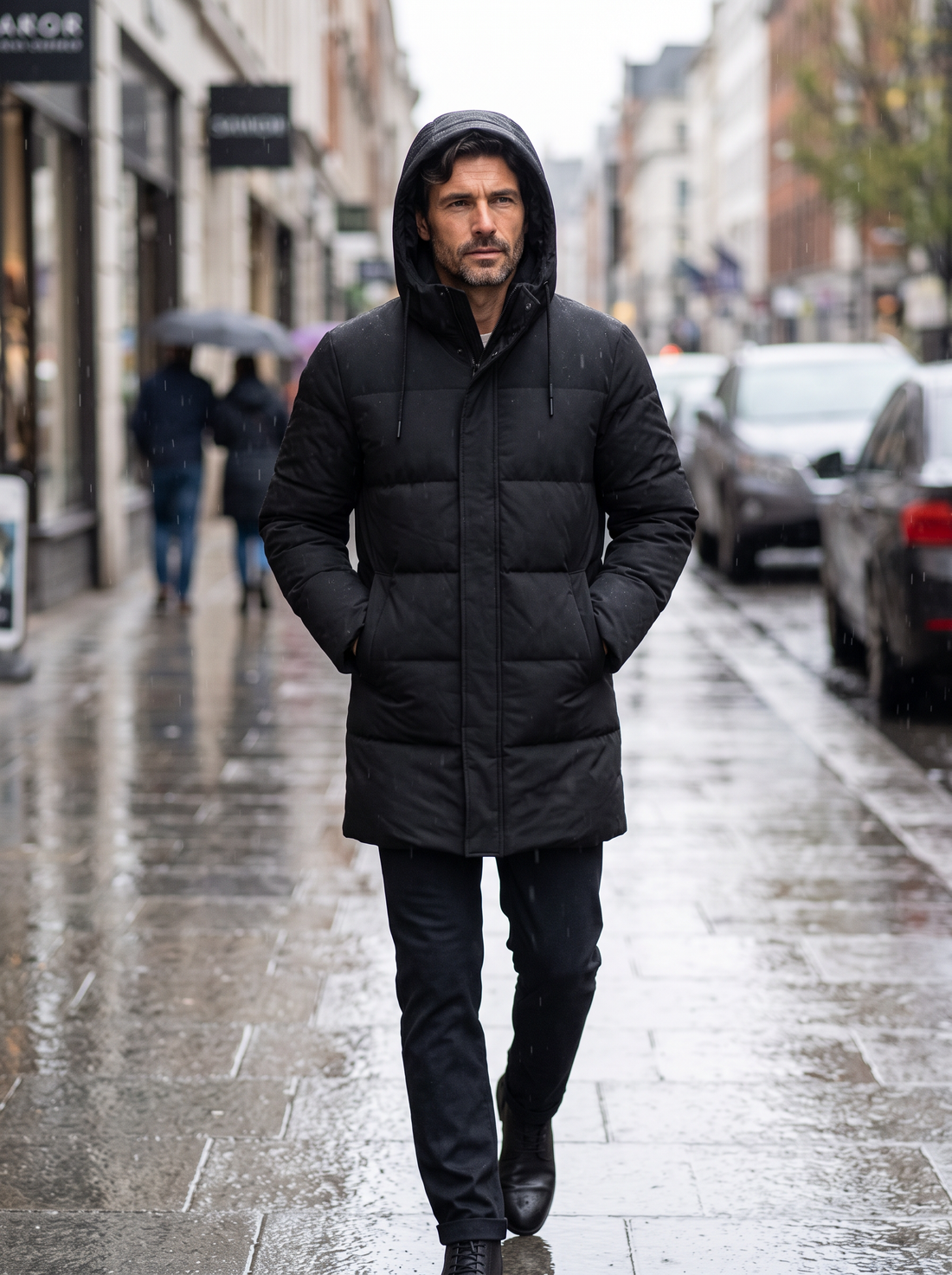 Man walking in the rain wearing black hooded waterproof puffer jacket
