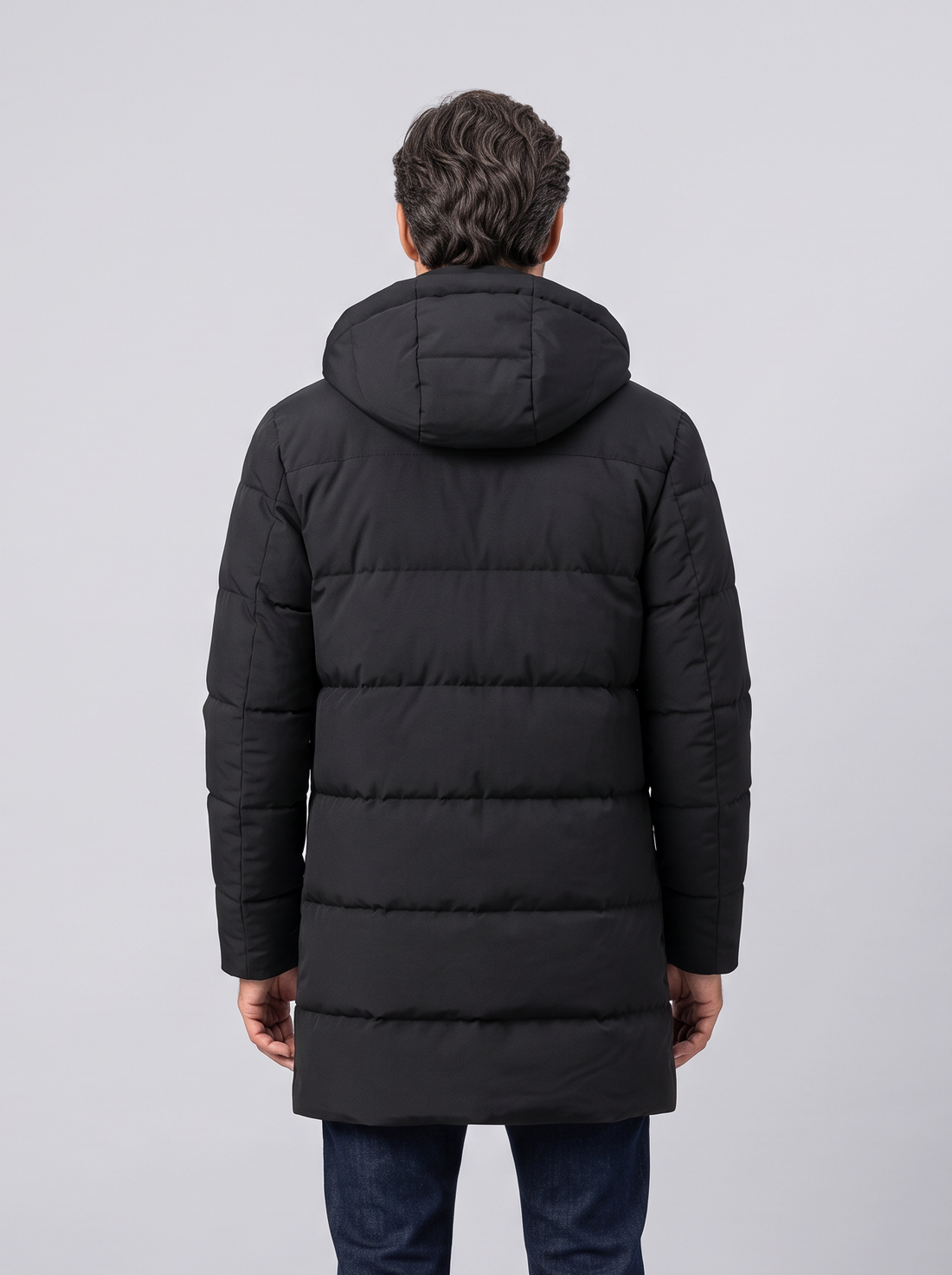 Man wearing black waterproof insulated long puffer jacket with hood, front view