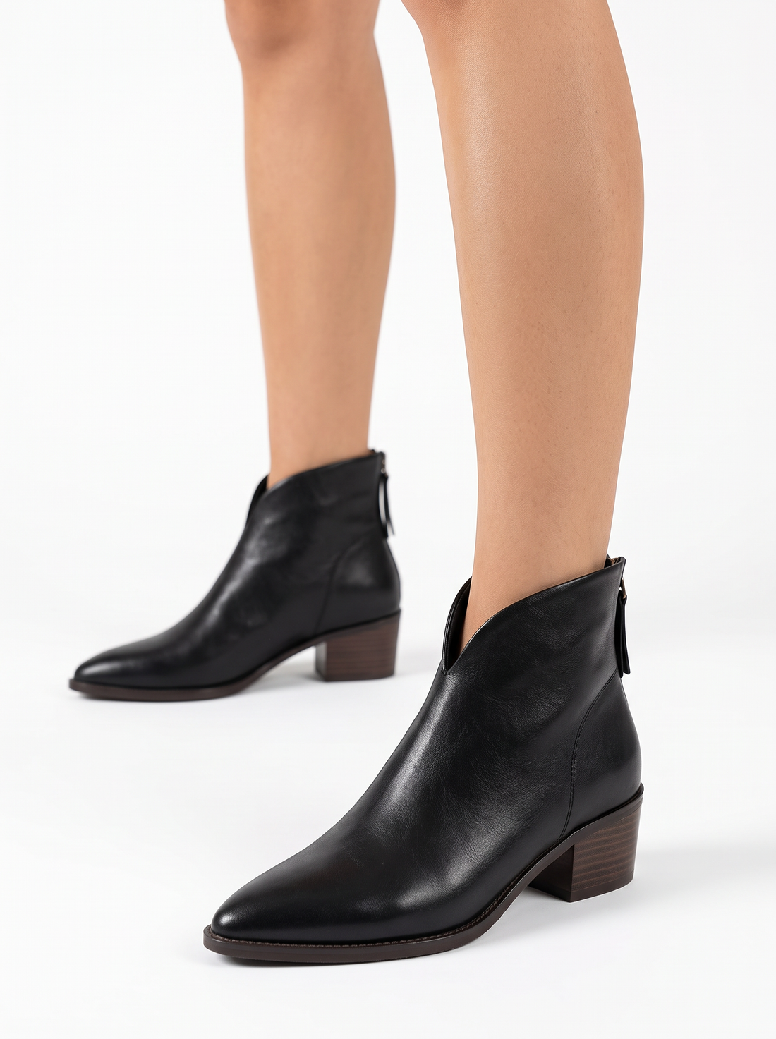 Women's black vegan leather pointed toe ankle boots with low block heel, worn, three-quarter view