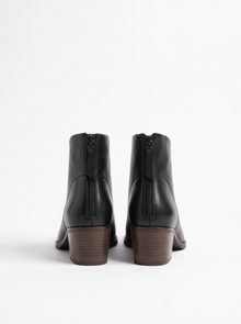 Back view of black ankle boots showing back zip and stacked heel