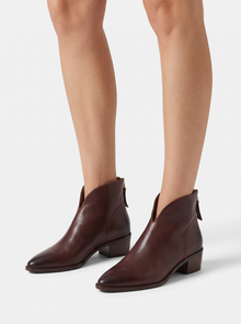 Women's brown vegan leather pointed toe ankle boots with low block heel, worn