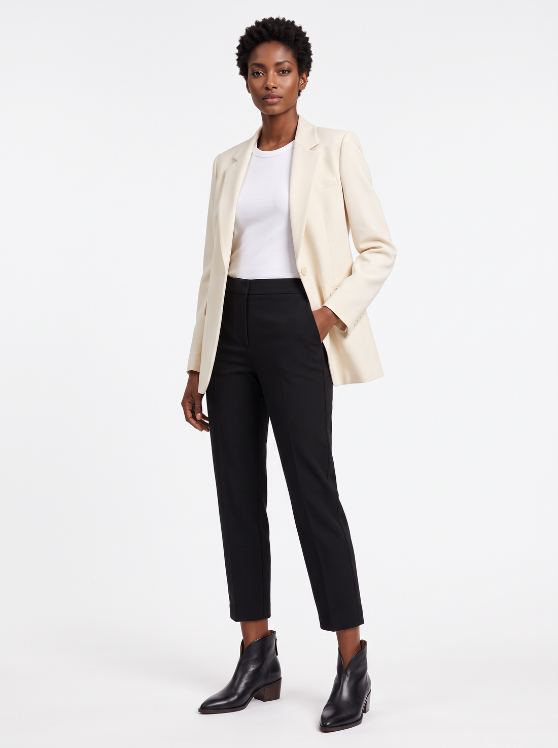 Woman wearing black pointed toe ankle boots with cream blazer and black cropped trousers