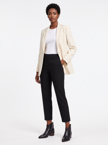 Woman wearing black pointed toe ankle boots with cream blazer and black cropped trousers