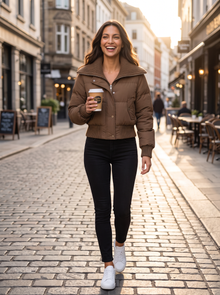 Woman walking in city street wearing brown cropped puffer jacket