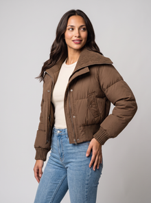 Brown cropped puffer jacket with ribbed knit collar, side view with jeans