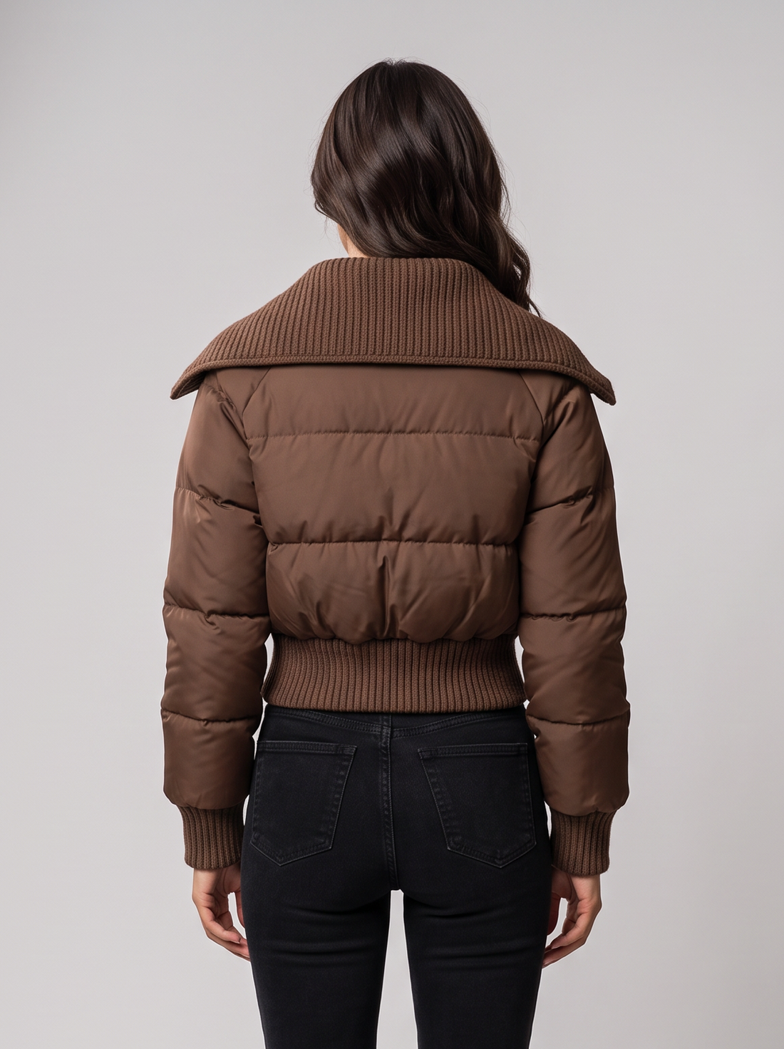 Woman wearing brown cropped puffer jacket with ribbed knit collar, front view