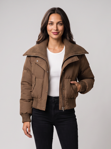 Woman wearing brown cropped puffer jacket with ribbed knit collar, front view