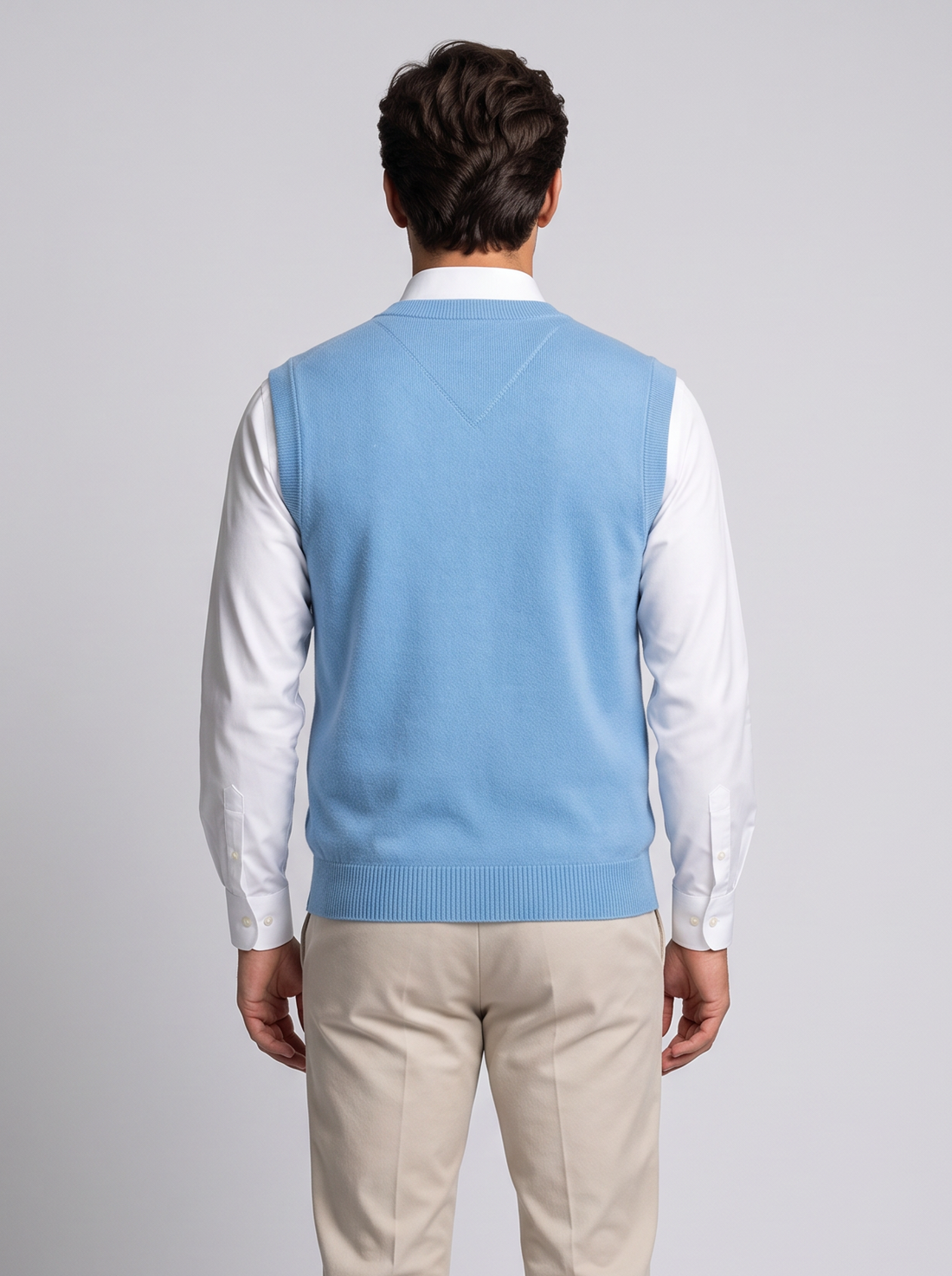 Man wearing blue merino wool V-neck sweater vest over white shirt, front view