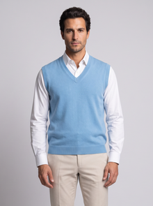 Man wearing blue merino wool V-neck sweater vest over white shirt, front view