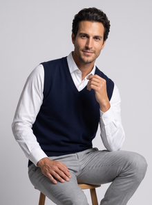 Man seated on stool wearing navy merino wool sweater vest