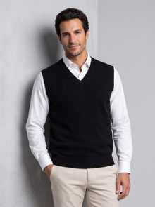 Man leaning on wall in black merino wool sweater vest
