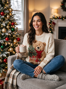 Woman with hot chocolate by Christmas tree wearing bear Christmas sweater