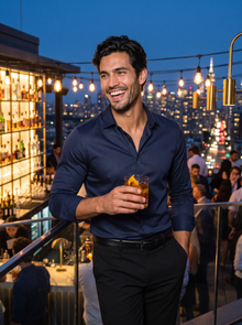 Man wearing navy satin-look dress shirt at a rooftop bar