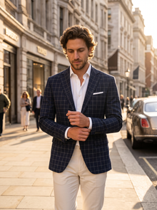 Man wearing navy windowpane blazer on a city street at golden hour