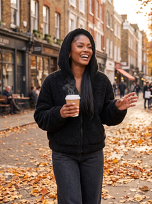 Woman wearing black teddy fleece jacket on an autumn city street