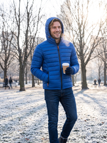 Man wearing a blue hooded puffer jacket in a winter park
