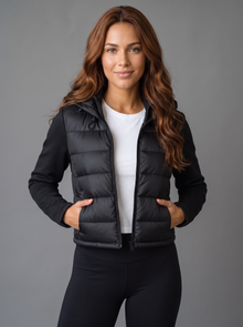 Woman wearing black cropped hooded puffer jacket, front view