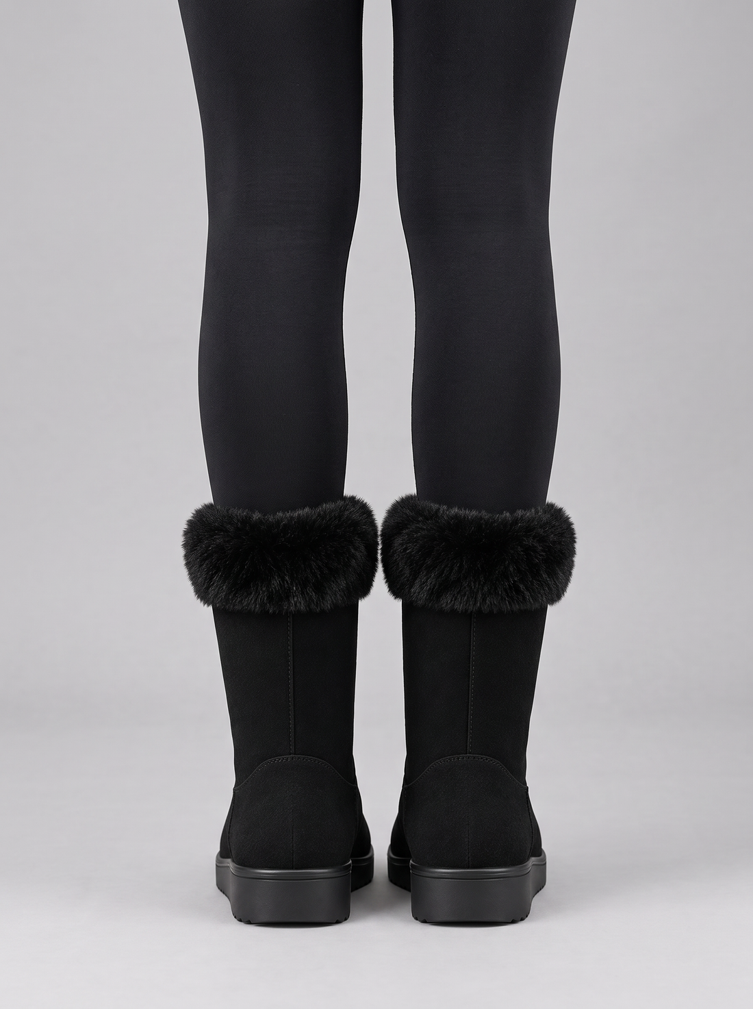 Back view of black mid-calf wedge boots with faux fur trim