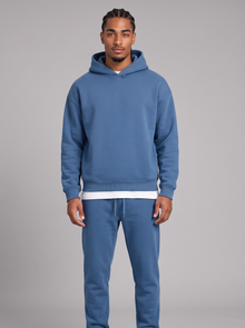 Men's blue oversized hoodie and tapered joggers tracksuit set with white tee, front view