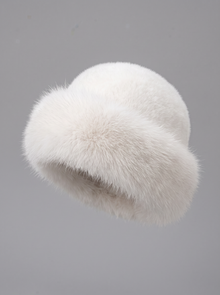 White faux fur Mongolian hat with ear flaps on a grey background