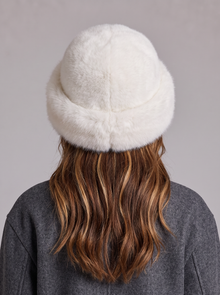 White faux fur hat with a rolled brim worn by a woman, back view